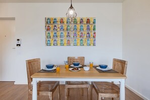 A dining area with a wooden table, four wicker chairs, and a colorful artwork above the table. - Antas Green Executive (Porto)