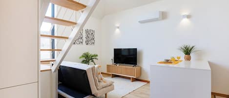 Ein modernes Wohnzimmer mit einer Couch, einem Fernseher und einer Treppe.