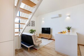 A modern living room with a sofa, TV, and a staircase. - Duque de Saldanha Duplex Loft (Porto)