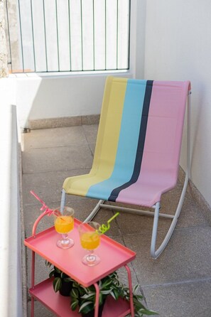 A rocking chair with a multicolored blanket, a small table with two drinks, and a potted plant. - Duque de Saldanha Duplex Loft (Porto)