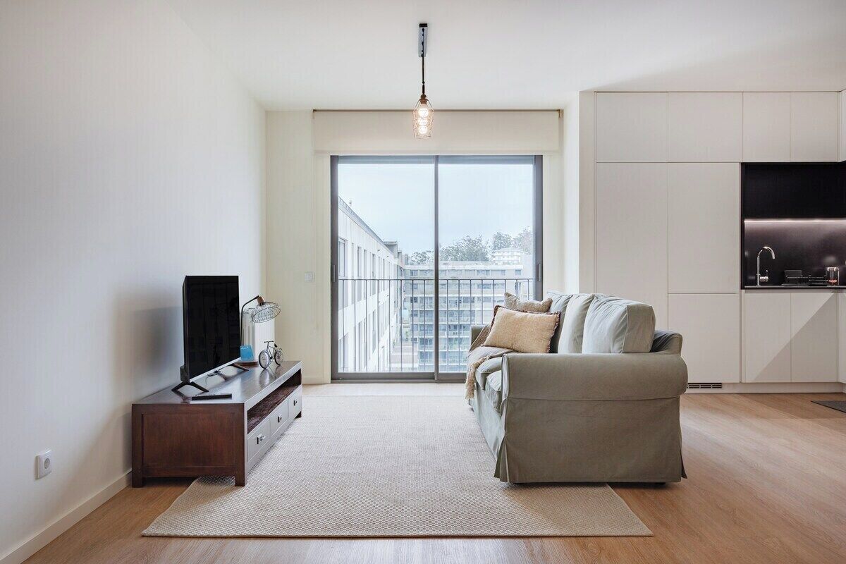 A modern living room with a sofa, a TV, and a kitchen area.