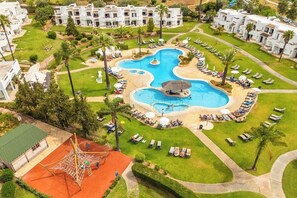 Ein Resort mit einem zentralen Swimmingpool, mehreren Liegebereichen und einem Spielplatz.