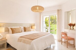 Une chambre à coucher avec un grand lit, des lampes de chevet, une chaise en bois, un miroir et une vue sur l’extérieur.