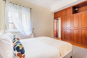 A bedroom with a bed, a window with sheer curtains, and a wooden wardrobe. - Marquês de Pombal Classical Living (Lisbon)