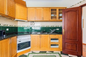 A kitchen with wooden cabinets, a stove, and a sink. - Marquês de Pombal Classical Living (Lisbon)