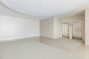 Un espace moderne pour les ascenseurs, doté d’un design épuré et minimaliste, comprenant deux ascenseurs et un mur sobre.
