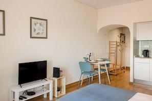 A room with a TV, a desk with a chair, a bed, and a kitchenette. - Sky View Studio em Cascais (Cascais)