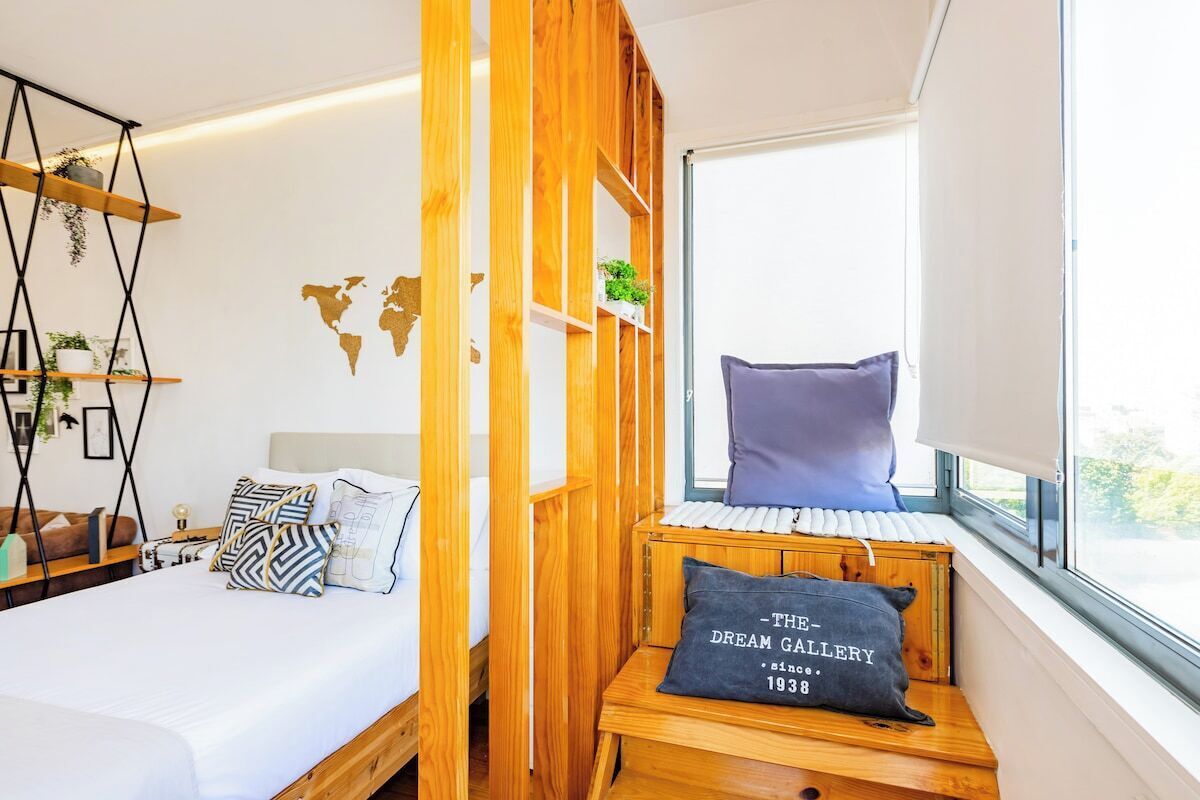 Une chambre à coucher avec un lit, une fenêtre donnant sur un beau paysage, une bibliothèque en bois et une carte du monde accrochée au mur.