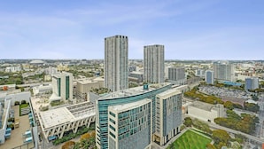 Una zona urbana con edifici moderni, una grande piazza aperta e uno stadio in lontananza.