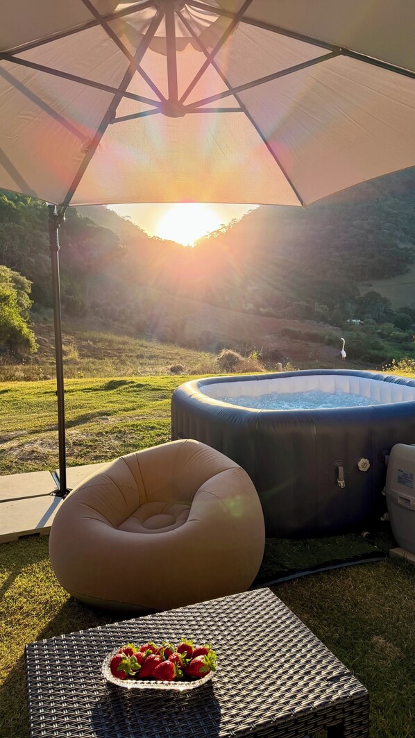 Un espacio al aire libre con jacuzzi, una tumbona y una mesa con fresas.