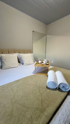A hotel room with a bed, a bedside table with a tray of tea and cups, and rolled towels on the bed. - Vale Refuge Azul | 3-bedroom house complete with stone hot tub Azul (Aracê)