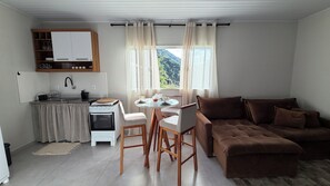 A compact kitchen with a stove, sink, and dining area with chairs and a table. - Vale Refuge Azul | 3-bedroom house complete with stone hot tub Azul (Aracê)