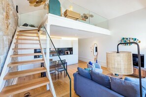 Ein modernes Interieur mit einer Holztreppe, einem Essbereich und einem Wohnzimmer mit Sofa und Lampe.