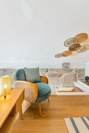 A cozy living room with a blue sofa, wicker chairs, a wooden table, and a stone wall. - Porto Loft Living (Porto)