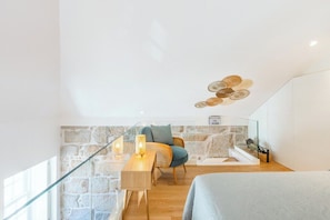 A modern room with a stone wall, a wooden desk, a wicker chair, and a bed. - Porto Loft Living (Porto)