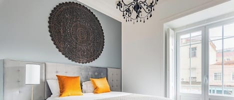 Ein Schlafzimmer mit einem großen Bett, einer Wanddekoration, einem Nachttisch und Blick durch ein Fenster.