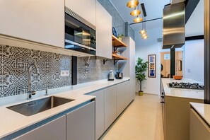 A modern kitchen with a built-in oven, stainless steel appliances, and a patterned backsplash. - Stylish 2BR Apartment | Ideal for Monthly Stays (Lisbon)