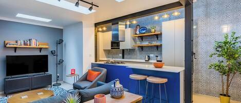 Ein moderner Wohnraum mit Küche, Essbereich und Fernseher in einer kompakten Wohnung.
