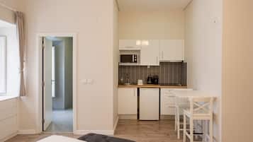 Una cocina compacta equipada con microondas, cafetera y refrigerador pequeño. Cuenta con un comedor con mesa y sillas.