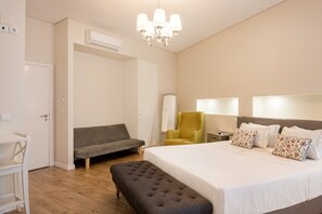 Ein Schlafzimmer mit Bett, einer Bank, einem Sofa, einem Sessel, einem Nachttisch und einer Lampe.