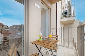 A balcony with a table, chairs, a bottle, and a glass of orange juice. - The Prime Loft @ BoaVista Flats (Porto)