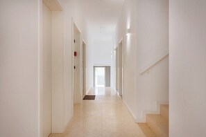 A long, narrow hallway with white walls and a tiled floor, leading to a door at the end. - The Prime Loft @ BoaVista Flats (Porto)