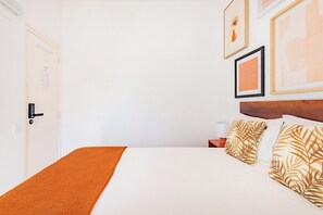 A hotel room with a bed, a nightstand, a lamp, and framed artwork on the wall. - Superior Suite @ Guest Inn 1 Boutique House (campo pequeno)
