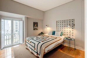 Ein Schlafzimmer mit Bett, Nachttisch, Lampe, einem Poster an der Wand und einer Balkontür.