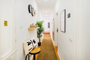 A hallway with a bench, a welcome sign, a potted plant, and framed pictures on the walls. - Suite Standard @ Guest Inn 1 Boutique House (campo pequeno)