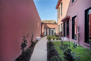 A narrow courtyard with a pathway, a small seating area, and a building with large windows. - Porto Center Duplex | Edifício Terracotta (Porto)