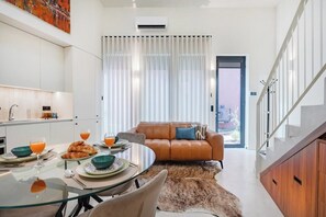 A modern living room with a glass dining table, leather sofa, and a fur rug. - Porto Center Duplex | Edifício Terracotta (Porto)
