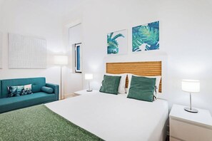 A hotel room with a bed, a sofa, a nightstand, and wall art. - Double Room with Sofa @ Guest Inn 1 Boutique House (campo pequeno)