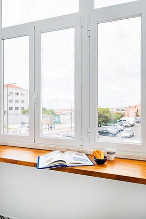 A window with a view of a street, a book, a bowl of bread, and a mug on a wooden ledge. - Graça's Urban Elegance (Lisbon)
