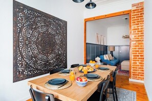 A dining area with a wooden table, black plates, and a decorative wall panel. - Graça's Urban Elegance (Lisbon)