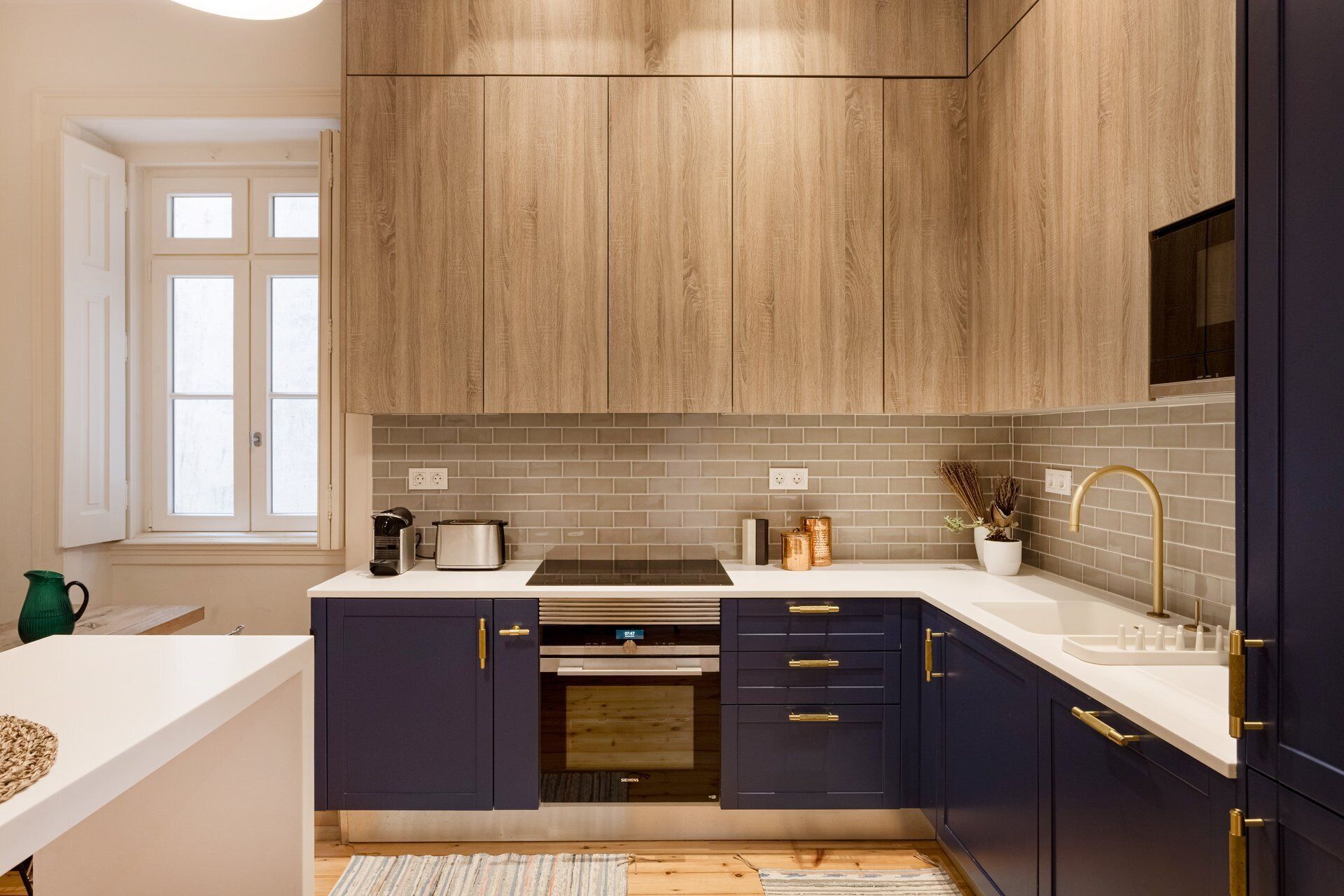 Una cocina moderna con armarios de madera, encimera blanca y horno integrado.
