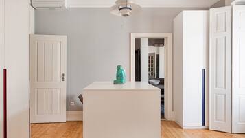 A hallway with white doors, a central island with a statue, and a ceiling light fixture.