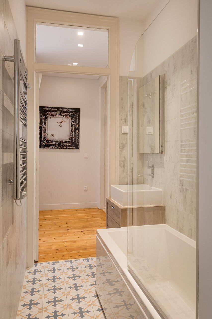 A bathroom with a bathtub, a shower, a wooden floor, and a tiled floor.