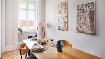 A dining area with a wooden table, chairs, a vase, and abstract paintings on the wall.