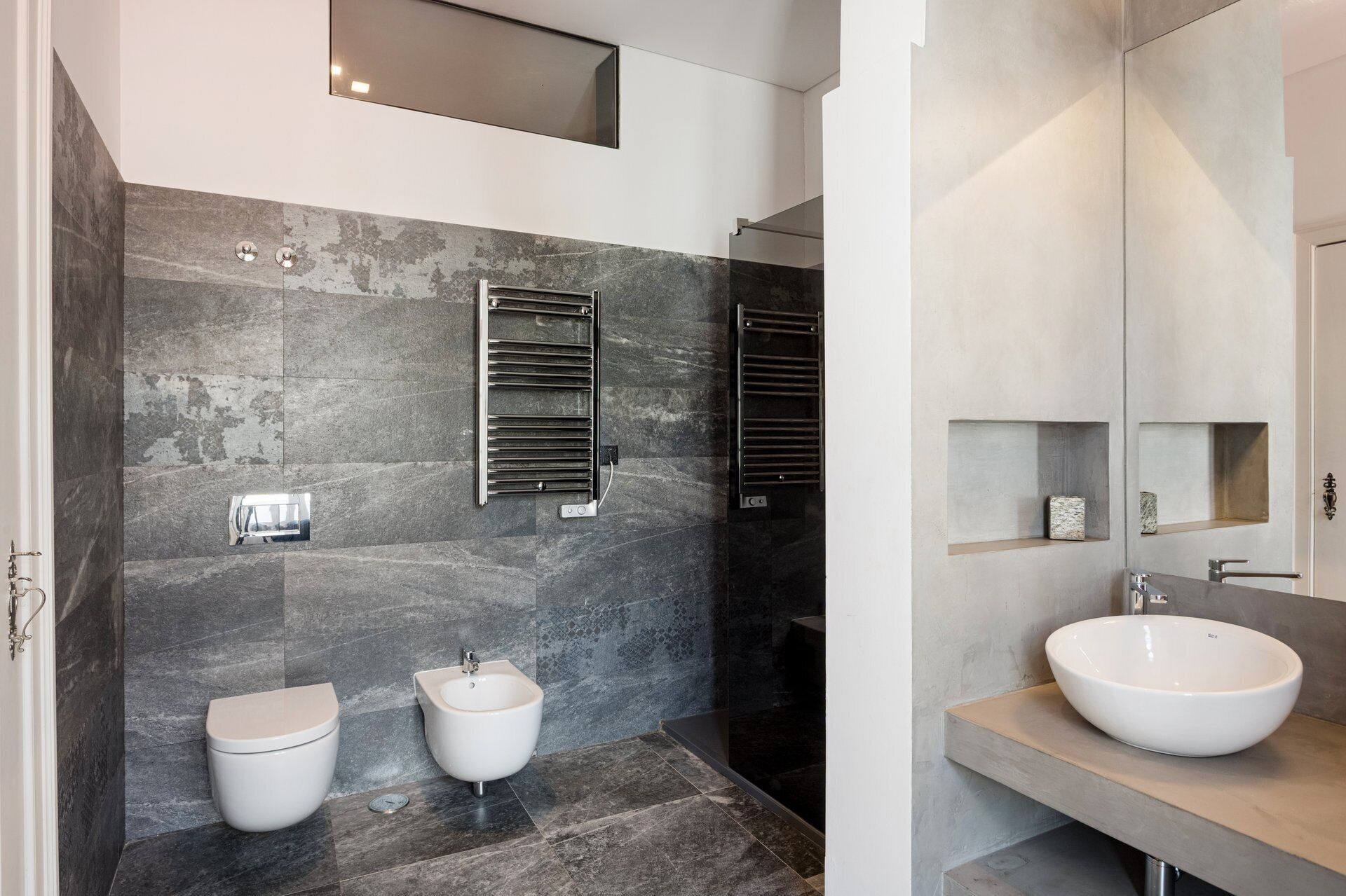 A modern bathroom with a bidet, toilet, and a large sink.