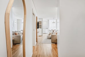 Ein modernes Interieur mit einem spiegelnden Wandbild aus Holz, einer Wohnbereits mit Sofas, einer Küche und einem Essbereich.