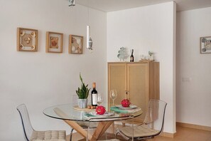 Ein Essbereich mit einem Glastisch, transparenten Stühlen, einem Holzschrank und gerahmten Bildern an der Wand.