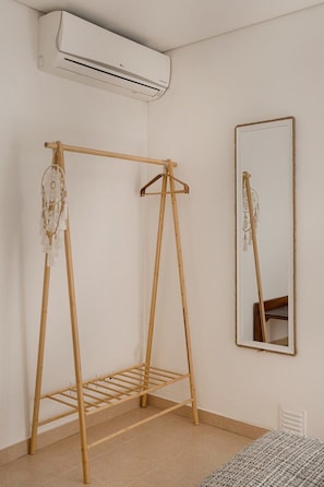 A room with a wooden drying rack, a mirror, and an air conditioning unit. - Vilamoura Garden Stay | Private Garden & AC (Faro)