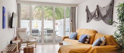 Una sala de estar moderna con un sofá, un sillón y un ventanal de vidrio que da a un espacio exterior.