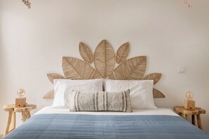 A bed with a woven headboard, white pillows, and a blue bedspread. - Vilamoura Garden Stay | Private Garden & AC (Faro)