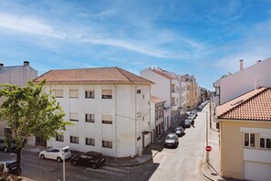 A narrow street lined with buildings, parked cars, and a clear sky. - Casa Magó (Espinho)
