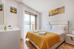 Une chambre à coucher moderne avec un lit, des tables de chevet, une fenêtre et des œuvres d’art accrochées aux murs.