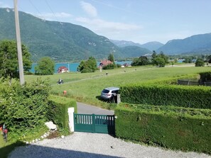 Ländliche Landschaft mit einem grünen Feld, einem geparkten Auto und einem Haus im Hintergrund.