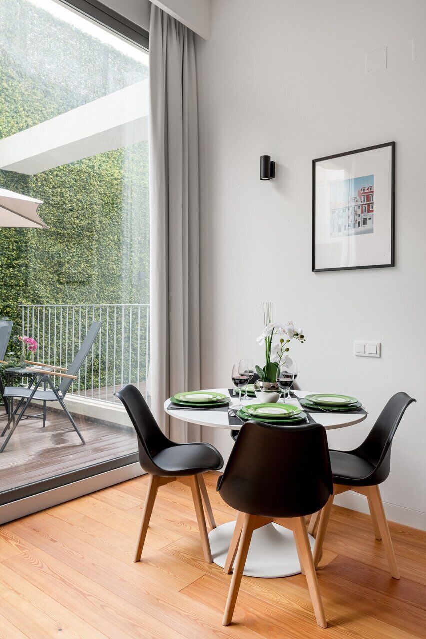 Un comedor moderno con una mesa redonda, sillas negras y vistas al exterior.