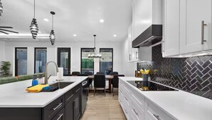 Een moderne keuken met een centraal eiland, witte kasten en een backsplash in een herringbone-patroon.