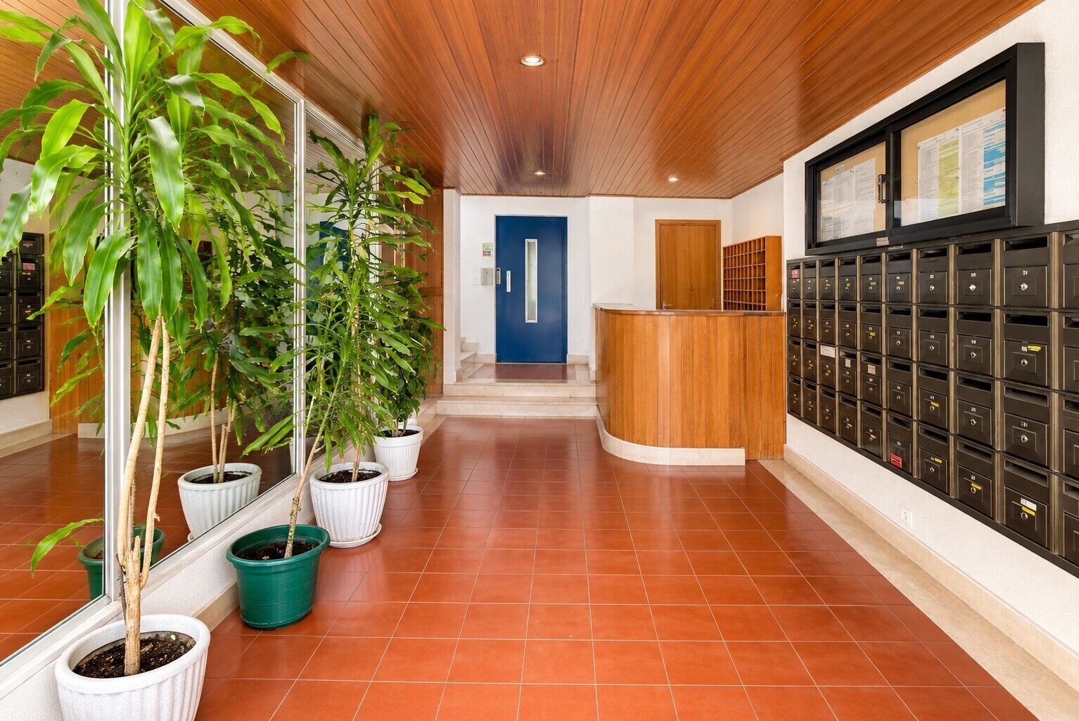 A reception area with a blue door, a wooden reception desk, and a row of black lockers.